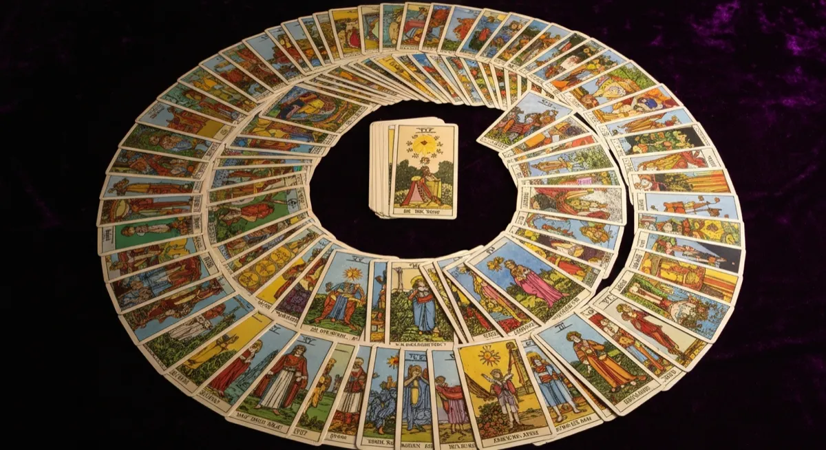 All 78 tarot cards fanned in a spiral on dark velvet surface